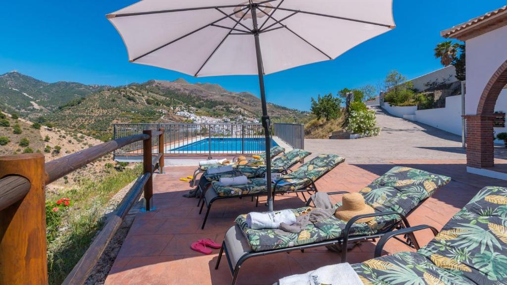 een patio met stoelen, een parasol en een zwembad bij Casa Rural Moreno Canillas de Albaida by Ruralidays in Canillas de Albaida