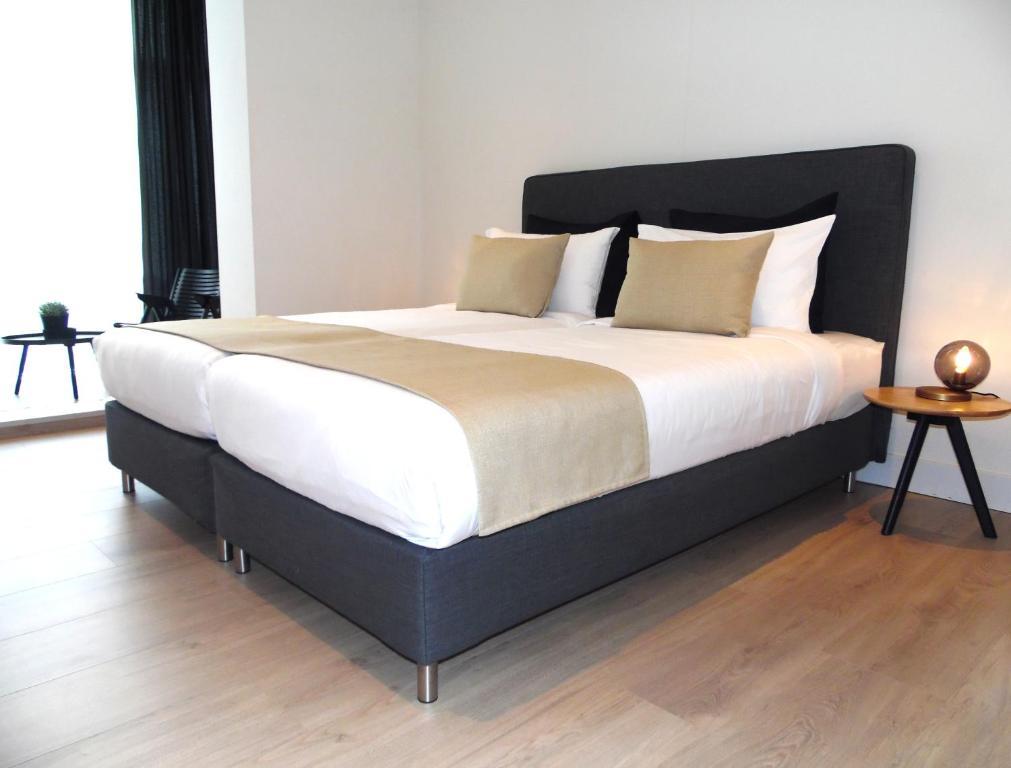 ein großes Bett mit weißer Bettwäsche und Kissen im Schlafzimmer in der Unterkunft Frankendael Apartments in Amsterdam