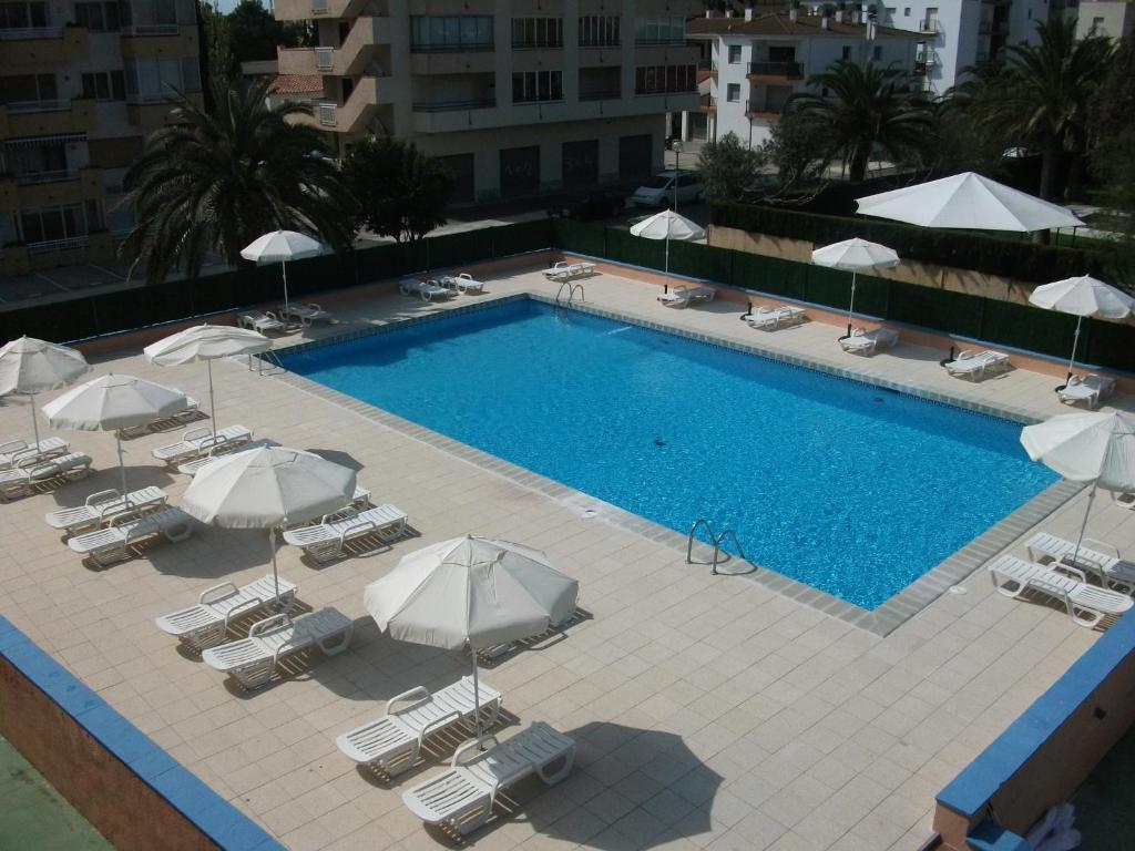 a large swimming pool with chairs and umbrellas at Nautilus Hotel in Roses