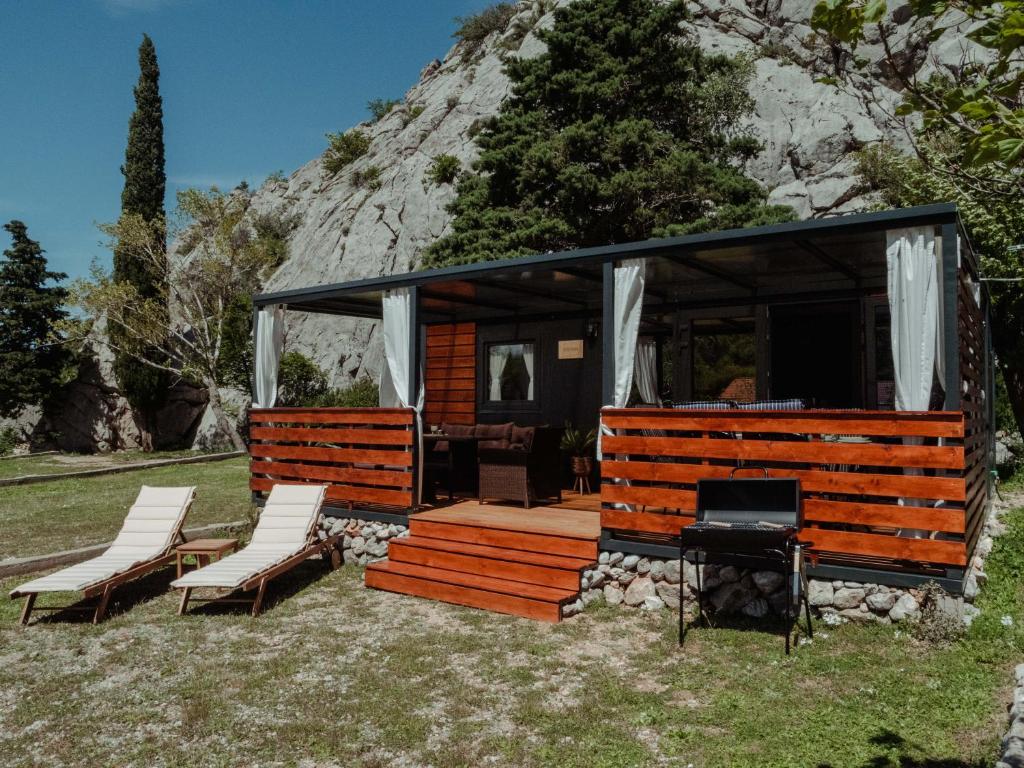 a cabin with chairs and a grill in the grass at Mobile home Amfora in Sveti Juraj