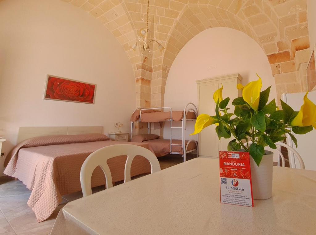 een slaapkamer met een bed en een tafel met een vaas met bloemen bij Casa Vacanza Fontana in Manduria