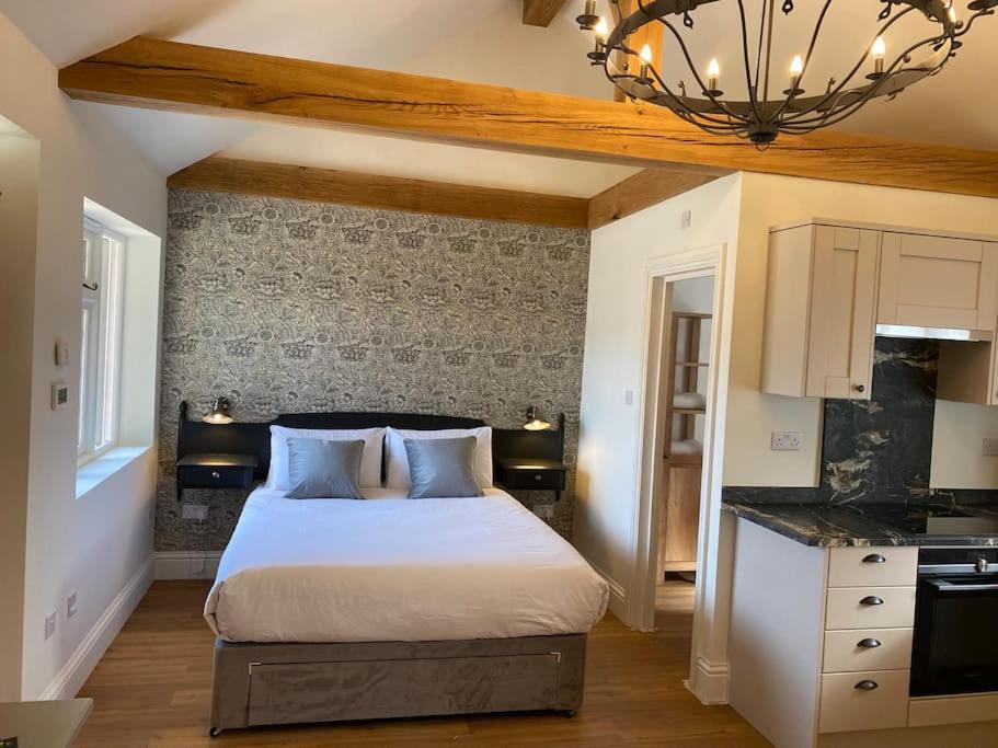 a bedroom with a bed and a kitchen with a chandelier at Luxury Self Catering Studio with vaulted ceiling in Ockley