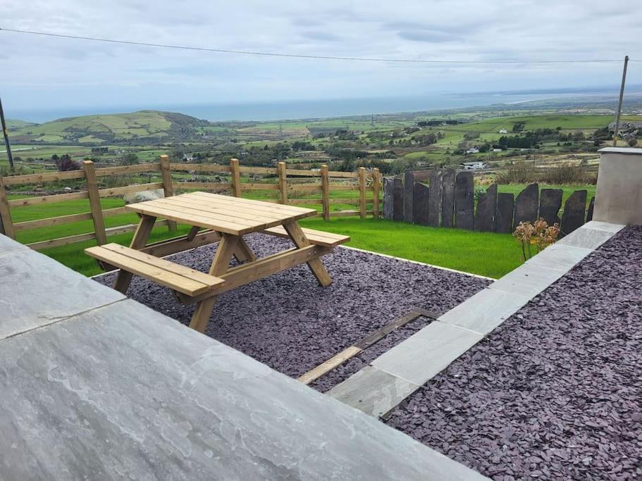 a wooden picnic table sitting on top of gravel at Amazing coastal & sunset views in Eryri (Snowdonia) in Llanllyfni