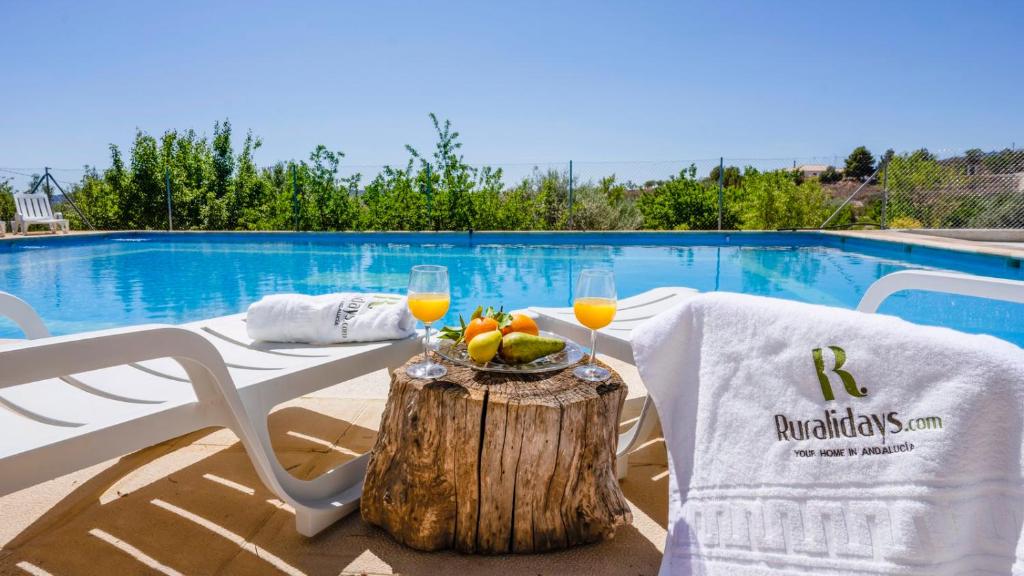 a table with a bowl of fruit and two glasses of orange juice at Cortijo El Álamo 1 Vélez Blanco by Ruralidays in Vélez Blanco