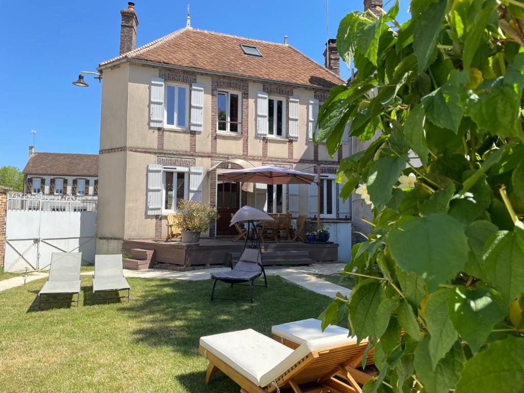 ein Haus mit einem Garten mit Stühlen und einem Sonnenschirm in der Unterkunft Villa Fontaine avec piscine intérieur chauffée in Fontaine-la-Gaillarde