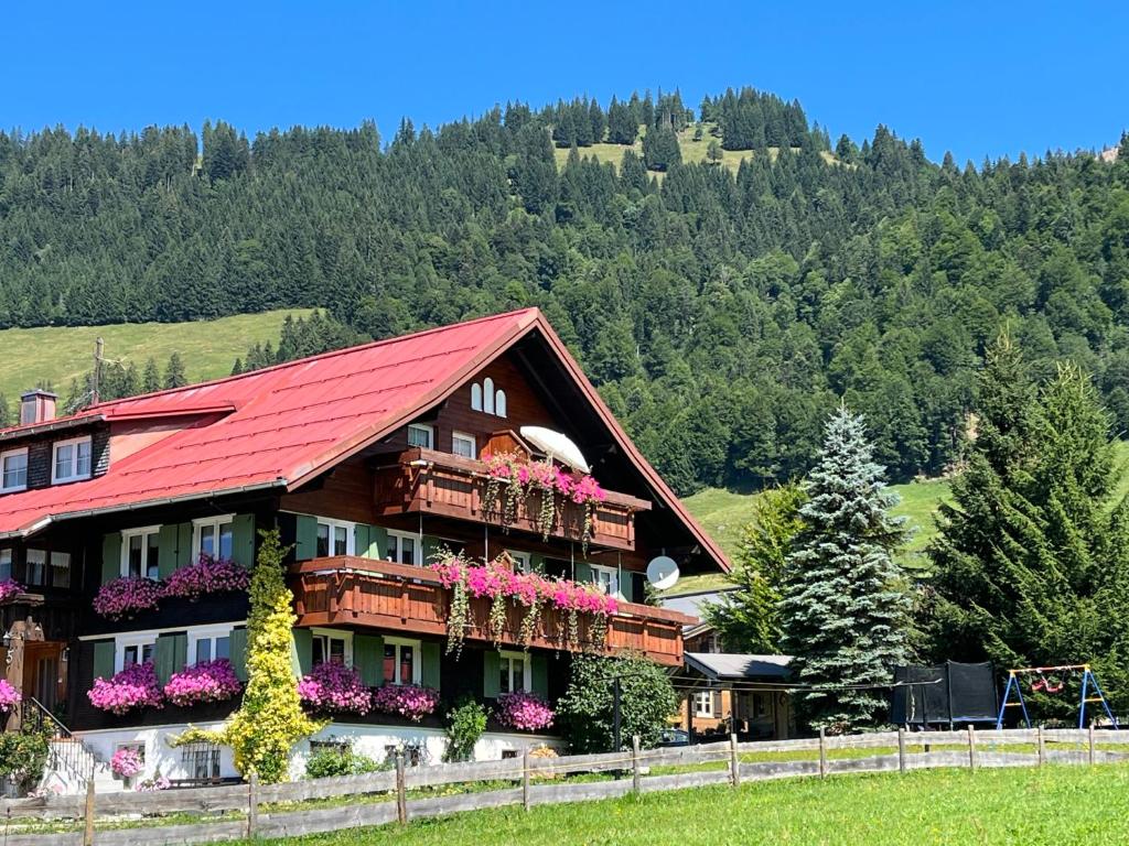 a house with a red roof and flowers on balconies at Gästehaus Nussbaumer in Balderschwang