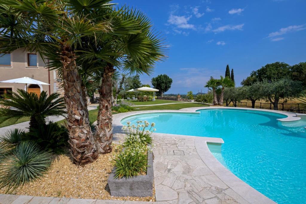 a swimming pool with palm trees next to a house at Villa Mario Resort in Salò