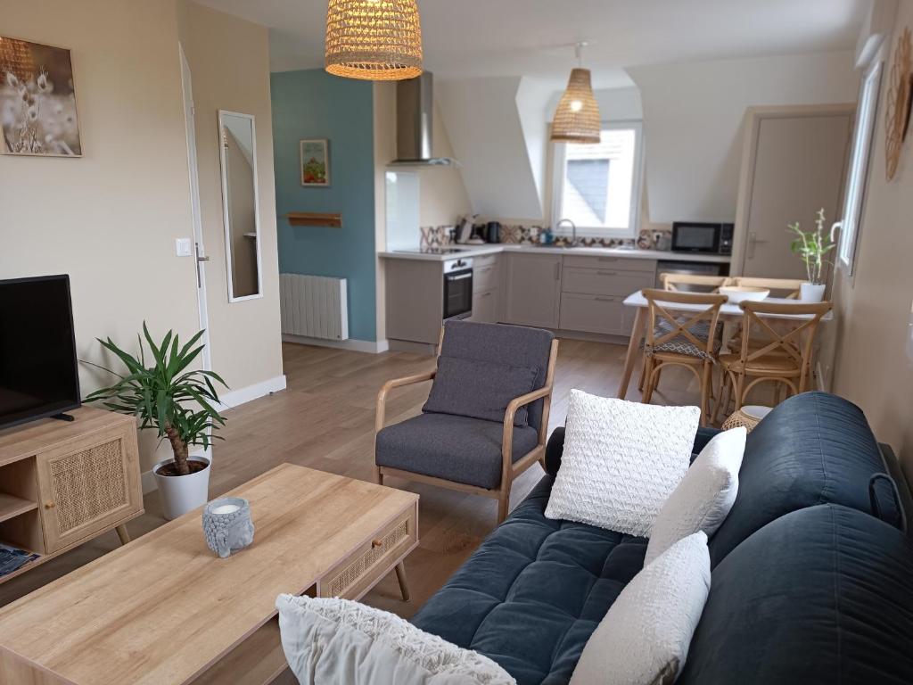 ein Wohnzimmer mit einem blauen Sofa und einer Küche in der Unterkunft Appartement Détente au Cœur du Cotentin in Valognes