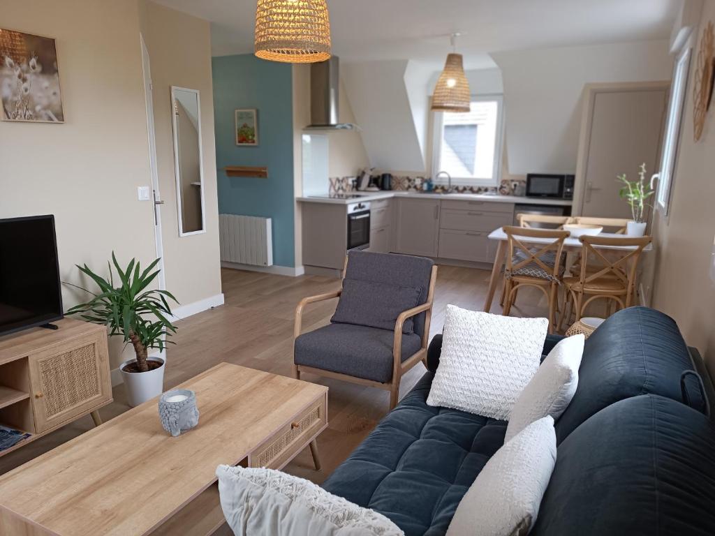 salon z niebieską kanapą i kuchnią w obiekcie Appartement Détente au Cœur du Cotentin w mieście Valognes