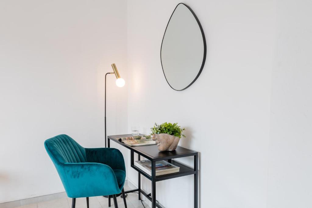 a blue chair and a table with a mirror at RELSTAY - Gae Aulenti - 1BR in Milan