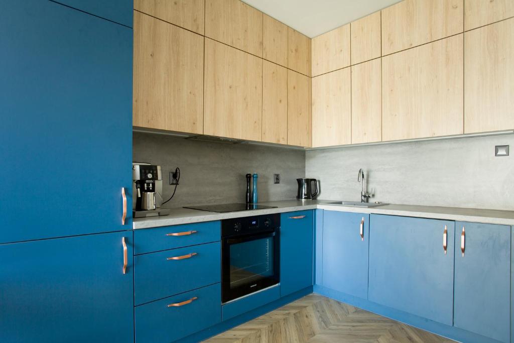 a blue kitchen with wooden cabinets and appliances at Oli&Joly Rybacka 12A in Kołobrzeg