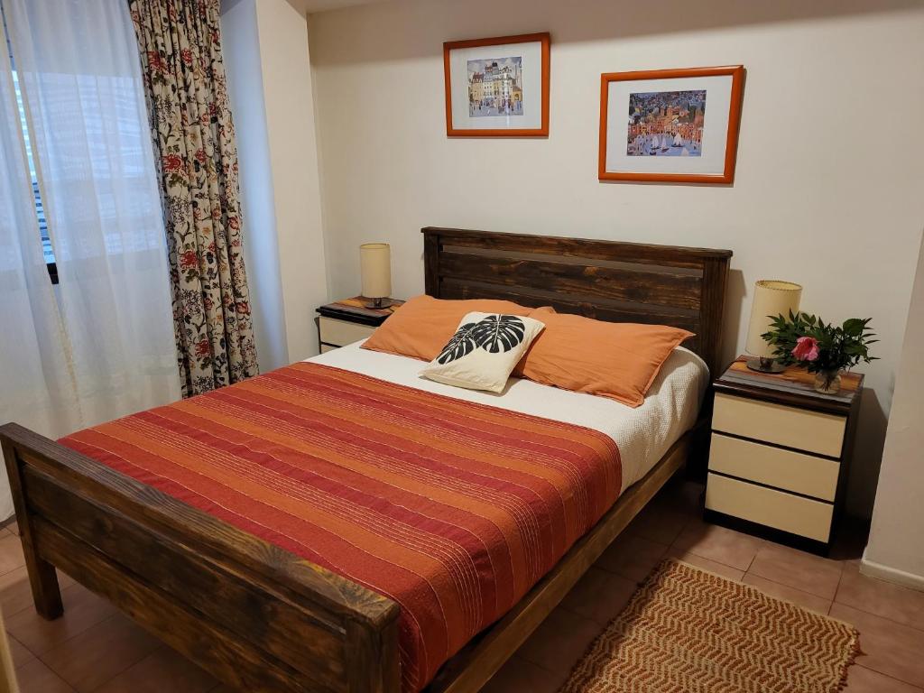 1 dormitorio con 1 cama con almohadas de color naranja en Guadalupe depto 2 amb con cochera macrocentro en Mar del Plata