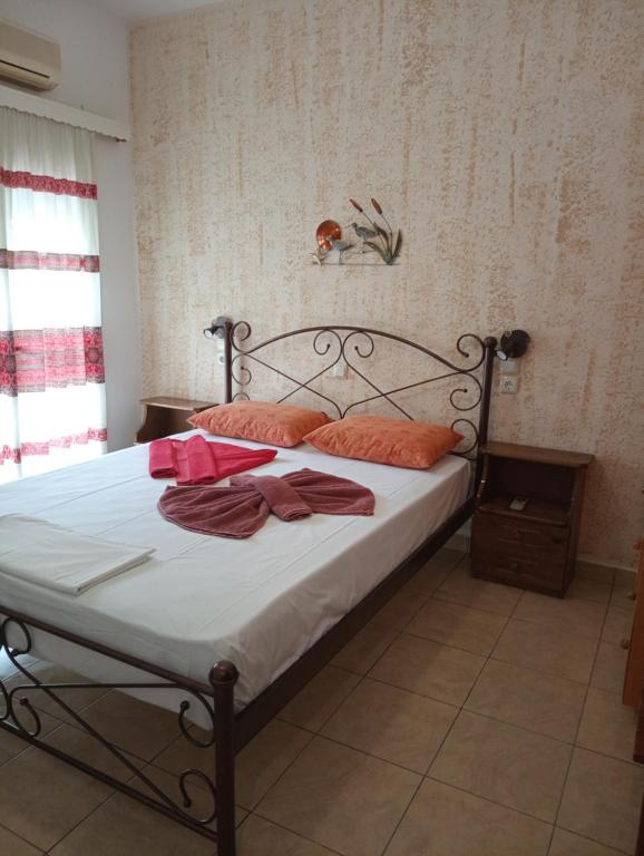 a bedroom with a bed with white sheets and orange pillows at Nektaria on the Beach in Fournoi