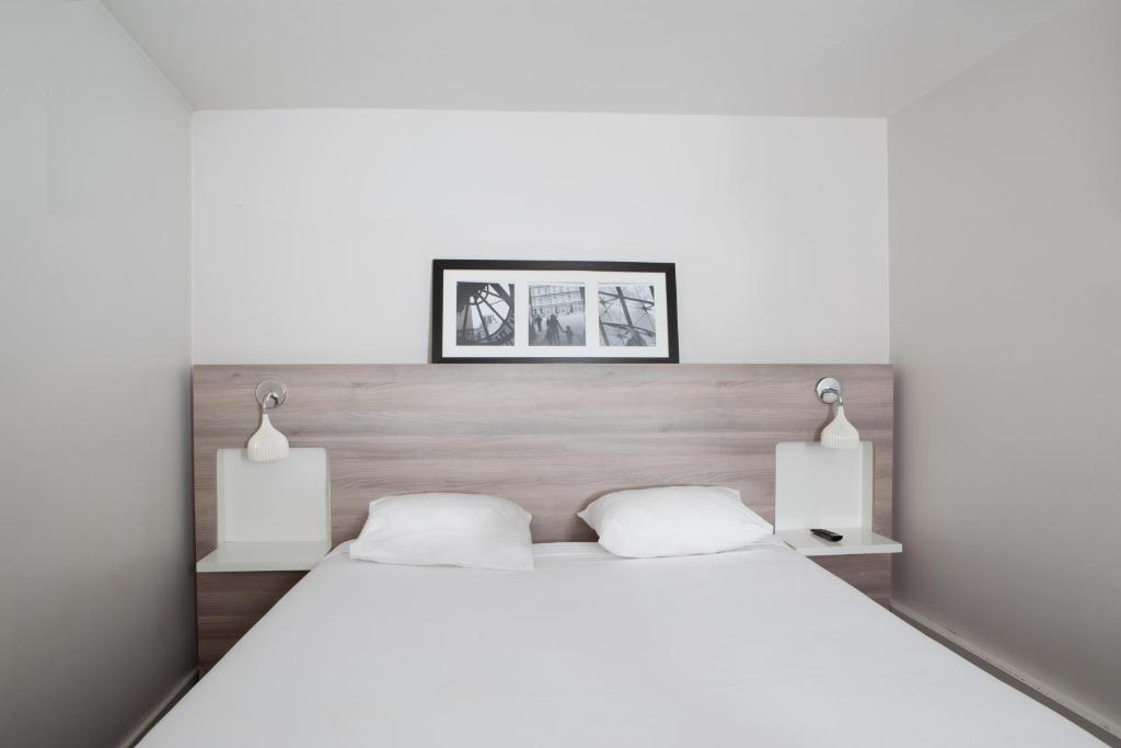 a bedroom with a large white bed with two lamps at Kyriad Paris Est - Bois de Vincennes in Saint-Maurice