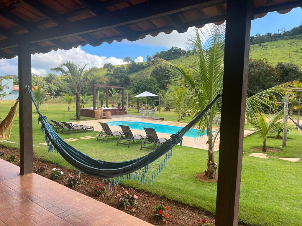 a hammock in the yard of a resort with a pool at Paraíso Capitólio "A Pousada da Dona Perpetua" in Capitólio