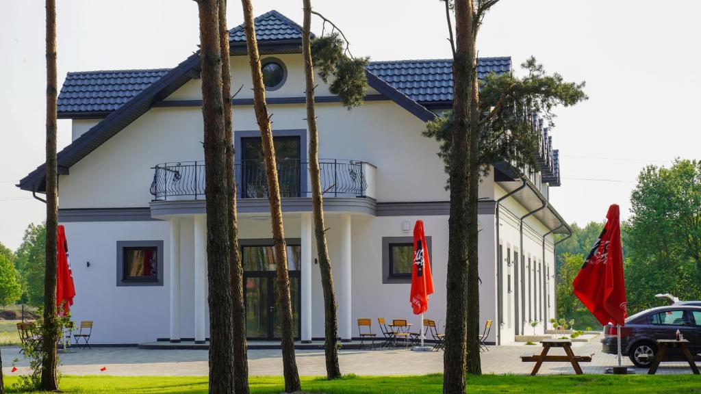 切霍齐内克Pensjonat Dębowy Dworek的一栋白色建筑，前面有树