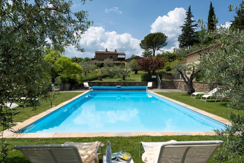 una gran piscina en un patio con 2 sillas en Villa Olivi, en Subbiano