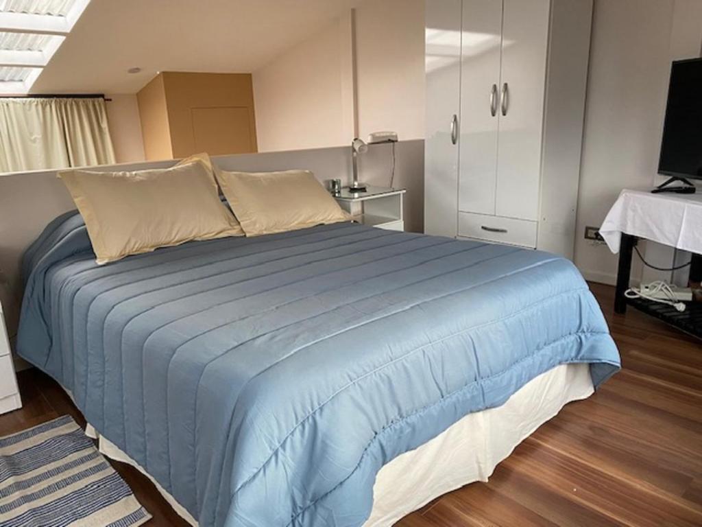 1 dormitorio con 1 cama azul grande en una habitación en Estudio en Ushuaia