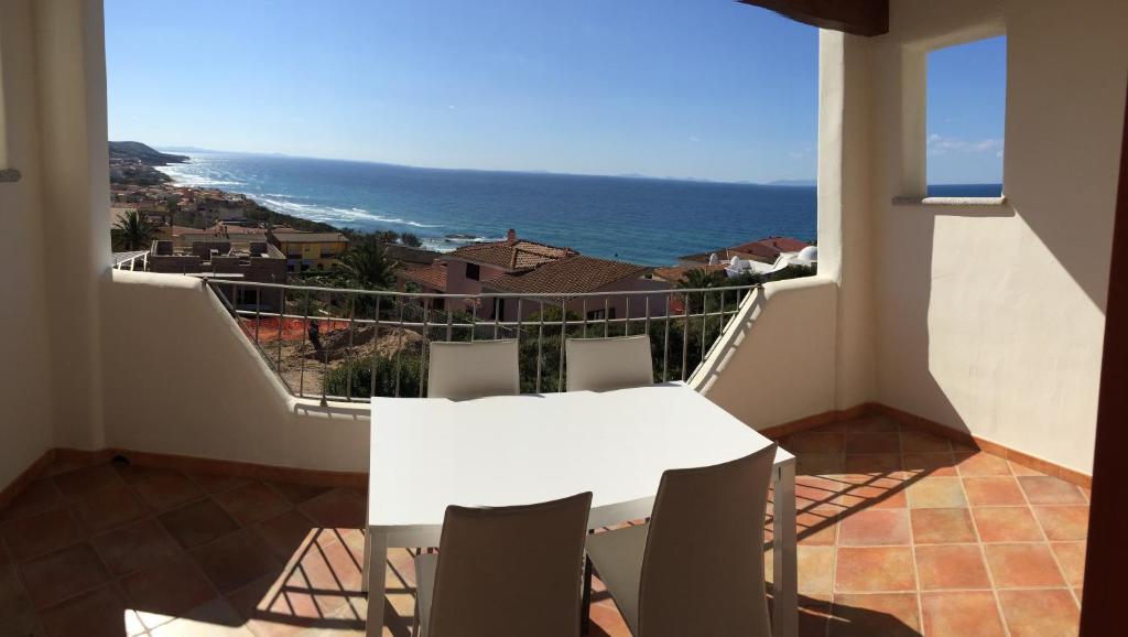 una mesa blanca y sillas en un balcón con vistas al océano en Residence Lentischi, en Castelsardo