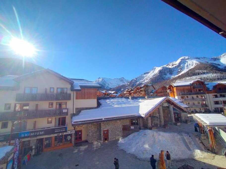 un groupe de personnes debout devant un immeuble avec neige dans l'établissement Vacances au coeur des Orres 1800, aux Orres