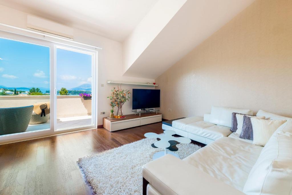 a living room with a white couch and a large window at Magic Sunset Suite in Dubrovnik