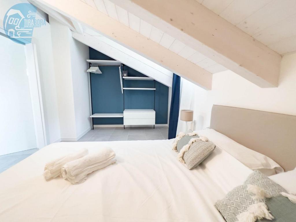 a white bed in a room with a blue wall at San Rocco Sweet Apartments in Muggia
