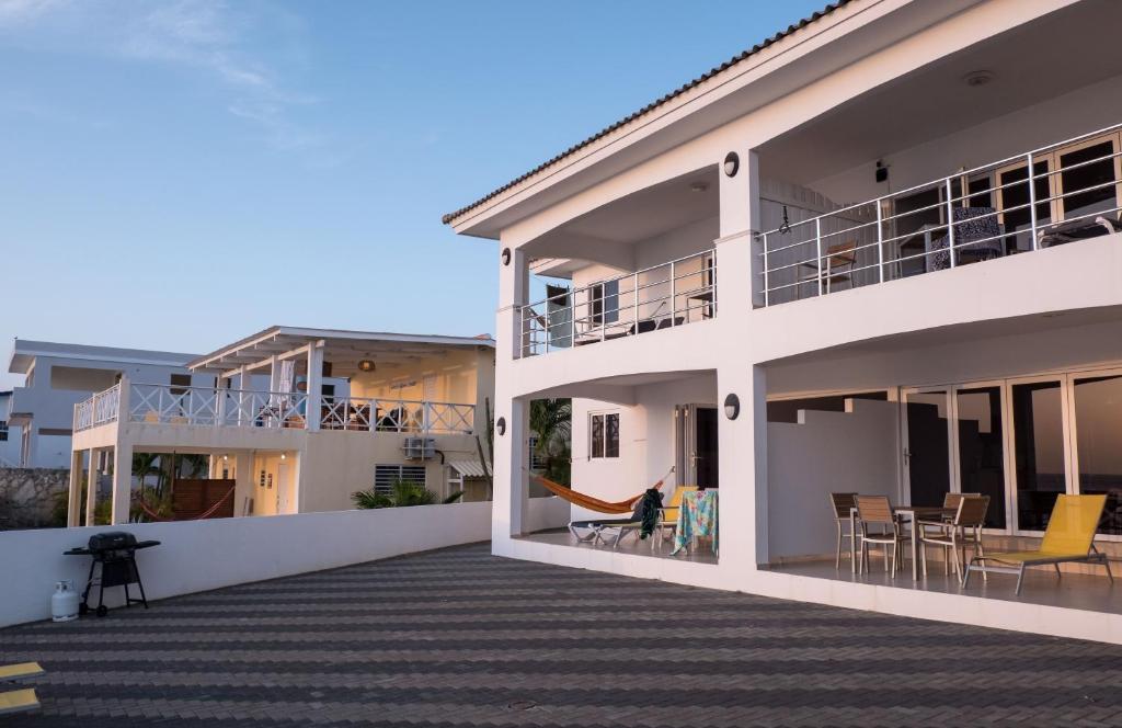 ein weißes Gebäude mit einem Balkon mit Stühlen und Tischen in der Unterkunft Whitehouse Lagun Apartments in Lagun