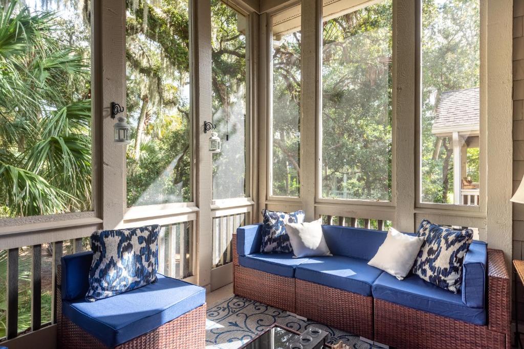 a porch with a blue couch and two chairs at 2766 Live Oak Villa in Seabrook Island