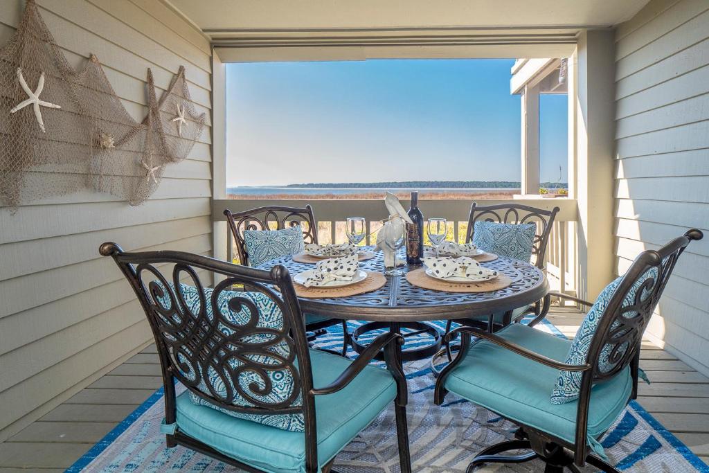 uma mesa e cadeiras num alpendre com vista para o oceano em 1331 Pelican Watch Villa em Seabrook Island