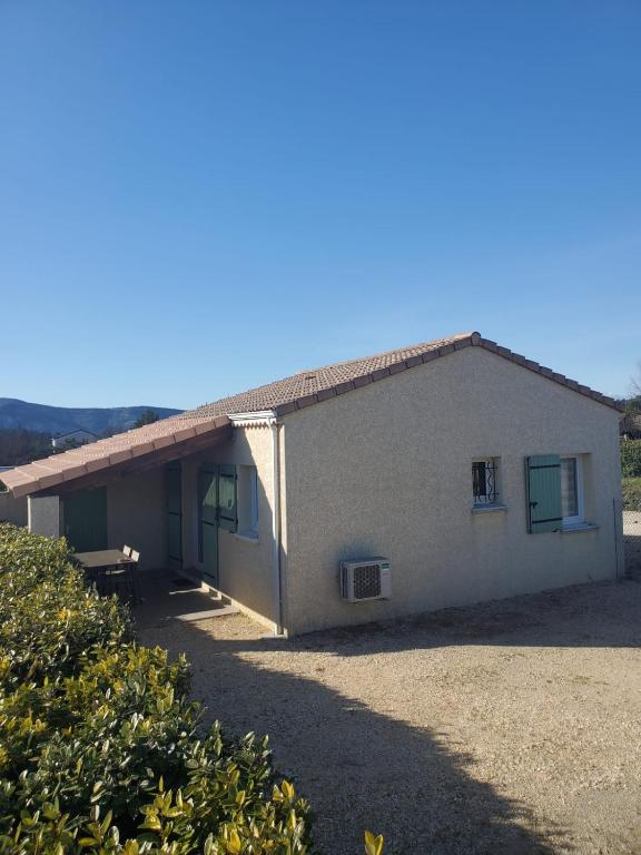 un petit bâtiment blanc avec des fenêtres à volets verts dans l'établissement Votre séjour à Vallon Pont D'Arc, à Vallon-Pont-dʼArc