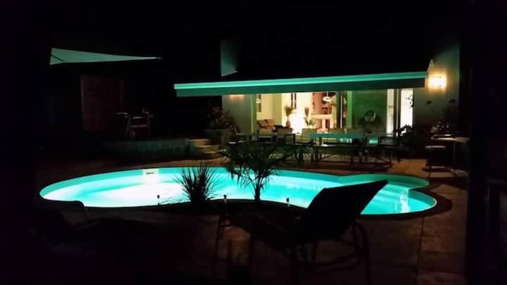 a swimming pool at night with a table and chairs at Villa DO MI SI LA DO RE in Labenne