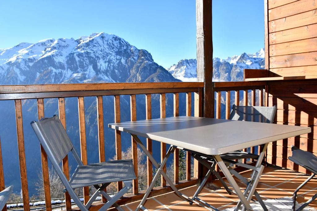 a table and chairs on a balcony with mountains at Appartement moderne vue imprenable in Villard-Reculas