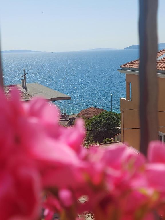 una ventana con vistas al océano y flores rosas en Apartman MB, en Podstrana