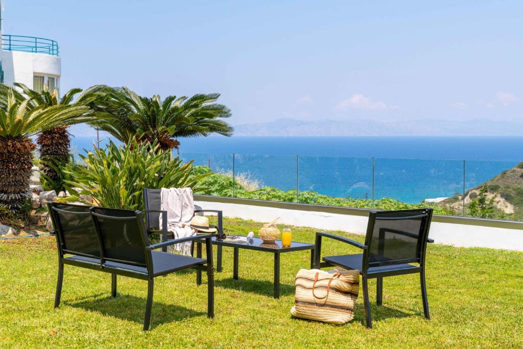 een tafel en twee stoelen op het gras met de oceaan bij Island Hills in Rhodos-stad