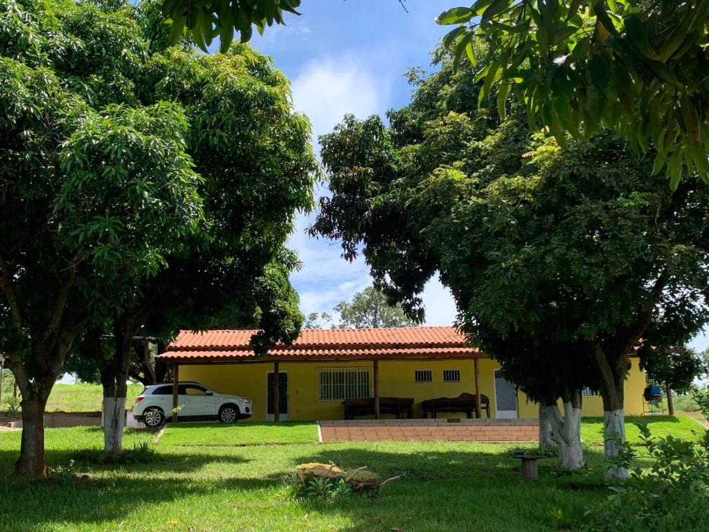 una casa amarilla con un coche aparcado delante de ella en CARAVELAS en Três Marias