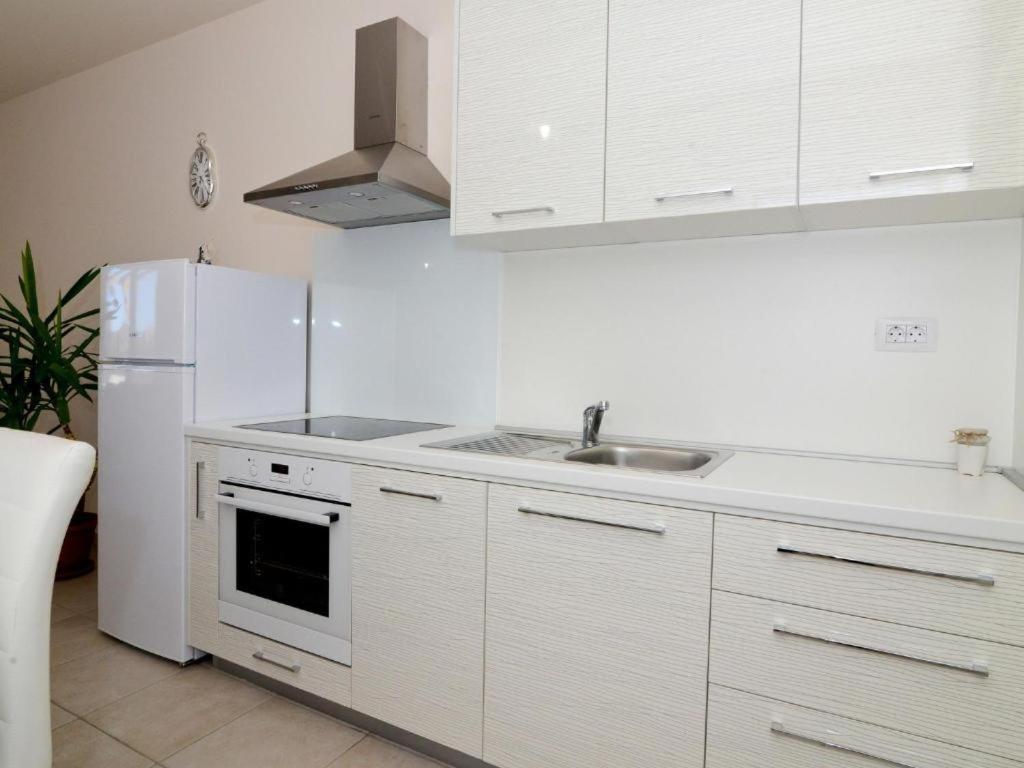 eine weiße Küche mit einer Spüle und einem Kühlschrank in der Unterkunft Apartmani Barbara in Ljubač