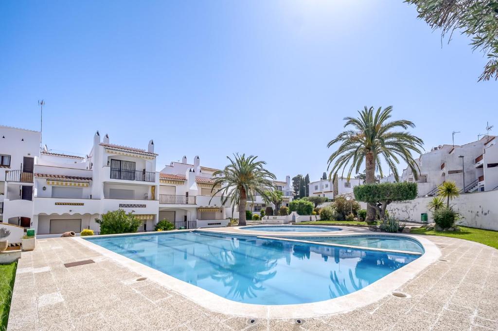 a villa with a swimming pool and palm trees at Jardins I 22 Roses - Immo Barneda in Roses