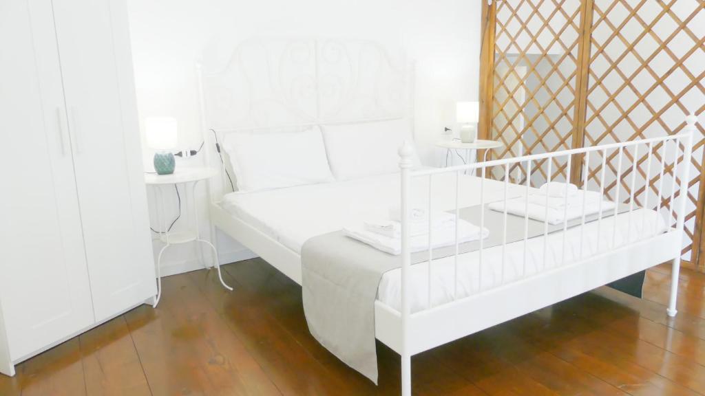 a white room with a white bed and a table at Marea Case per Vacanze in Bacoli