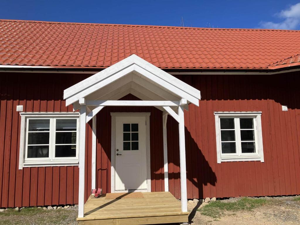a red house with a wooden porch and a white door at Svanen B&B in Karlsborg