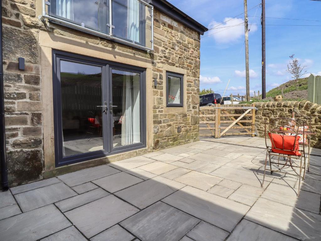 a patio with a red chair and a building at Cuckoo Cottage in Keighley