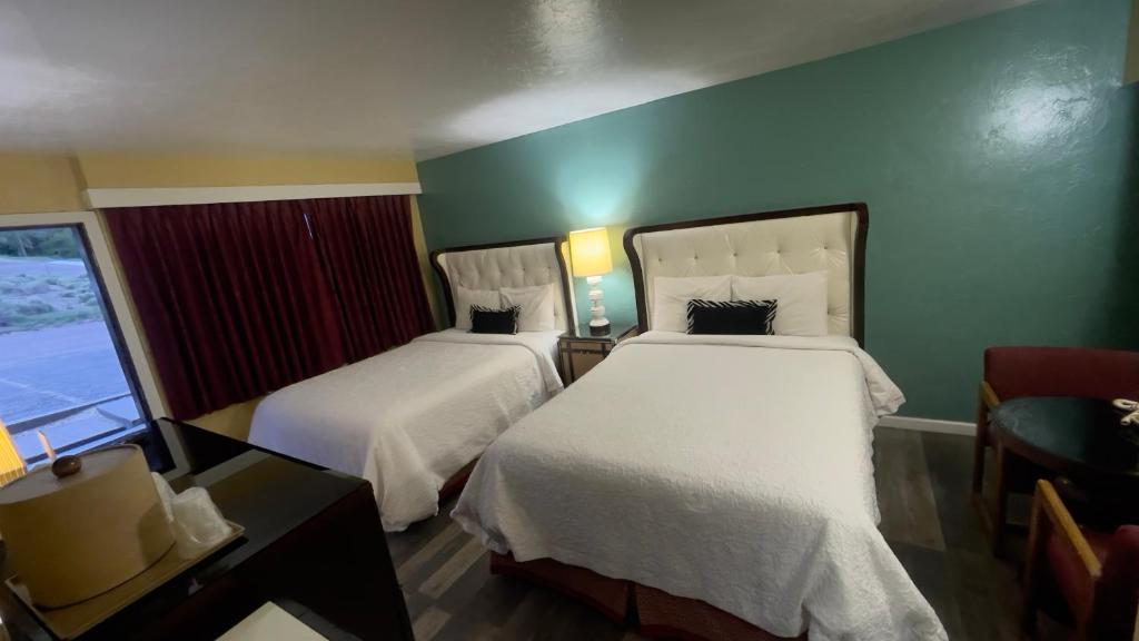 エルコにあるAmerican innのベッド2台と窓が備わるホテルルームです。