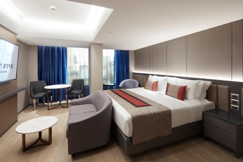 a hotel room with a bed and a tv at Grace At Five by Grace Hotel Bangkok in Bangkok