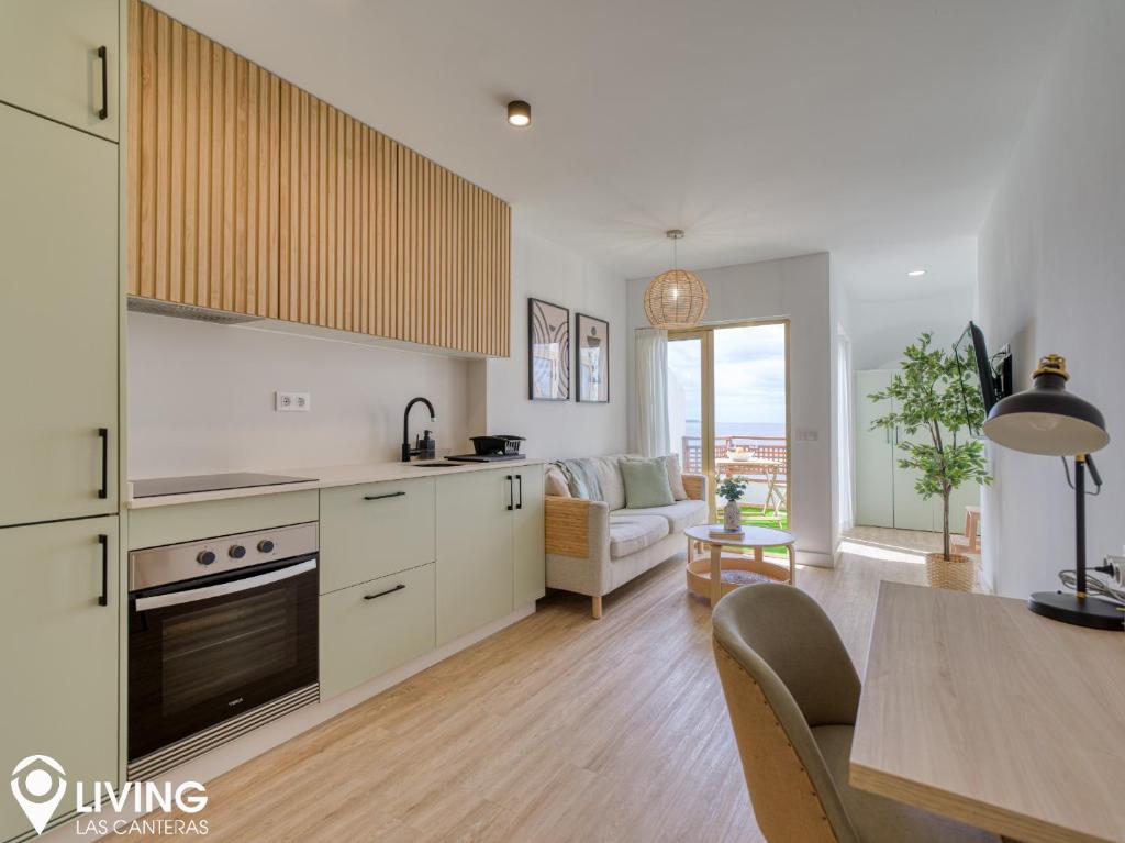 a kitchen with white cabinets and a living room at Living Las Canteras Homes - BEACHFRONT IN STYLE in Las Palmas de Gran Canaria