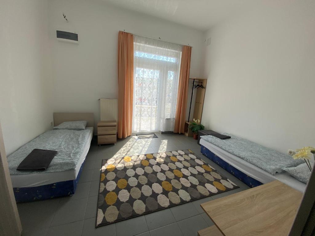 Habitación con 2 camas y alfombra en el suelo en Tocc Apartman, en Gyál