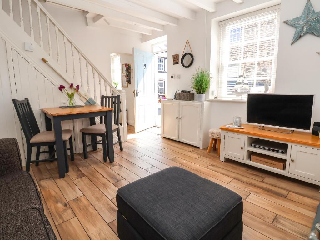 a living room with a table and a television at Sandy Shell Cottage in Conwy