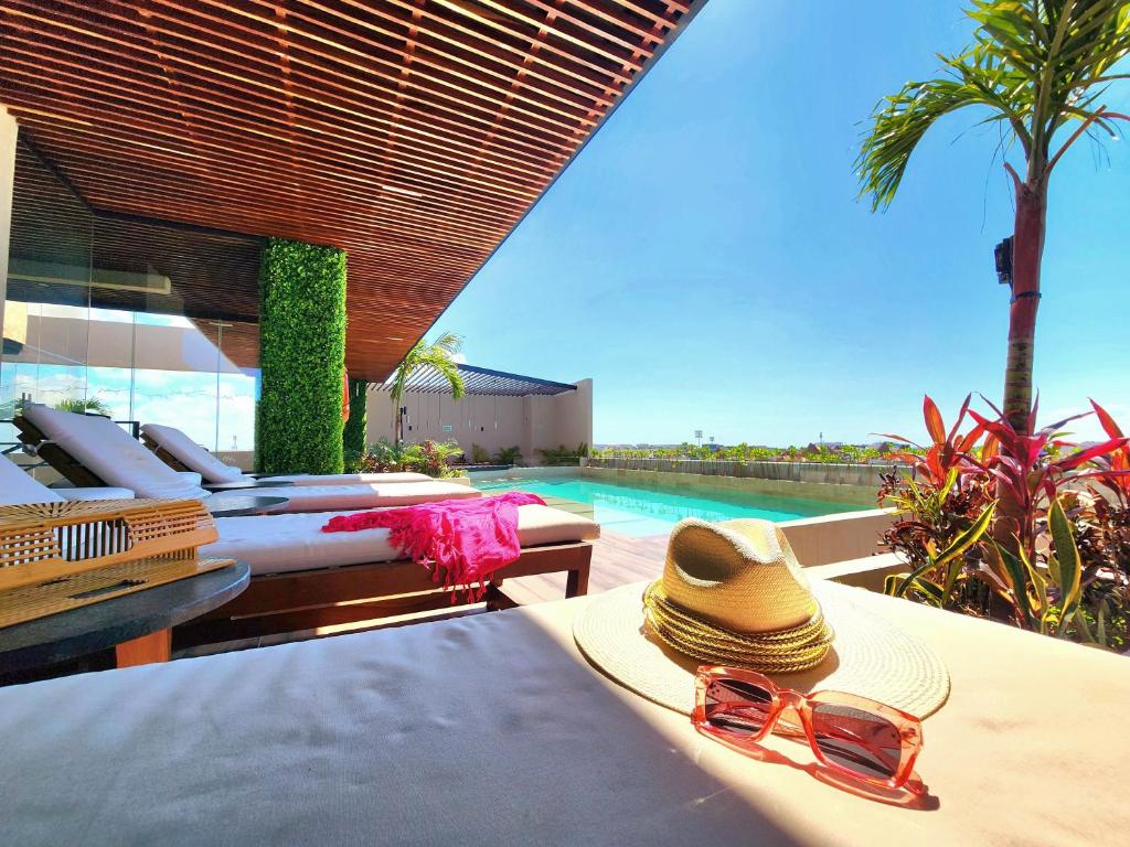 un sombrero y gafas de sol sentados en una mesa junto a una piscina en Sofía Boutique Condos by Bunik en Playa del Carmen