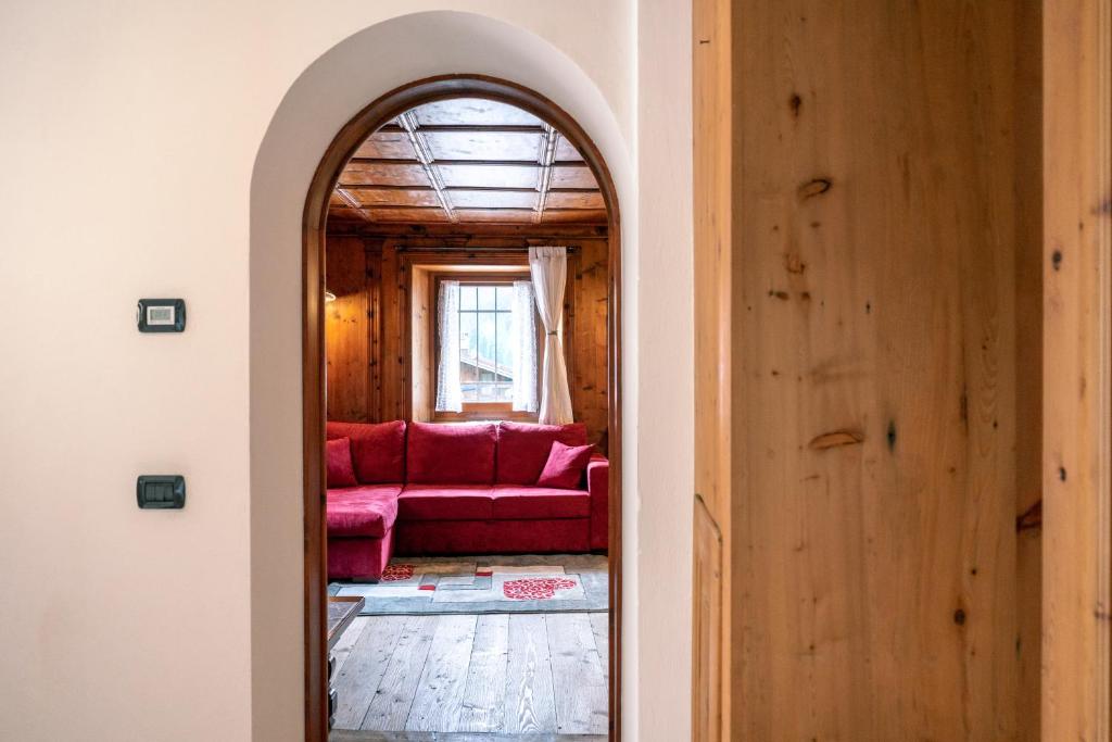 een boog leidt naar een woonkamer met een rode bank bij Appartamento La Tana sulle Dolomiti in San Vito di Cadore