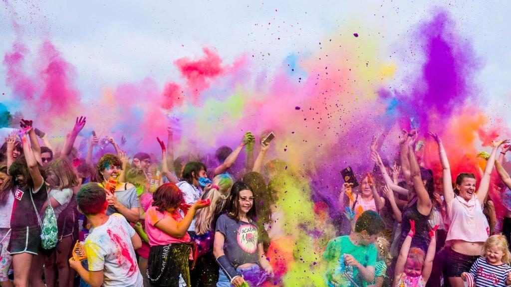 a group of people standing in front of a crowd covered in colors at Ryan Beachfront - Bossa in Sant Josep de Sa Talaia