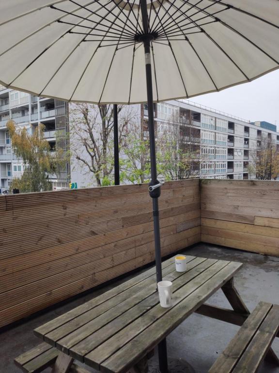 a wooden bench with an umbrella on a balcony at City Lodge Shadwell in London