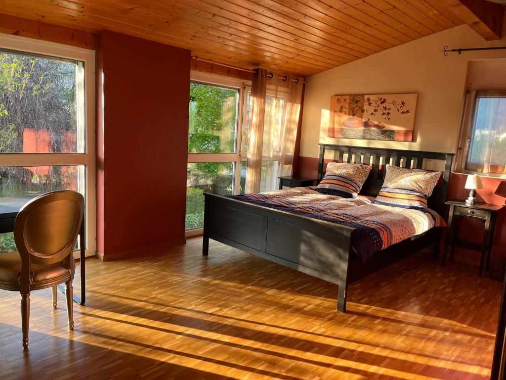 a bedroom with a bed and a chair and windows at Chambres dans villa avec piscine in Veyrier